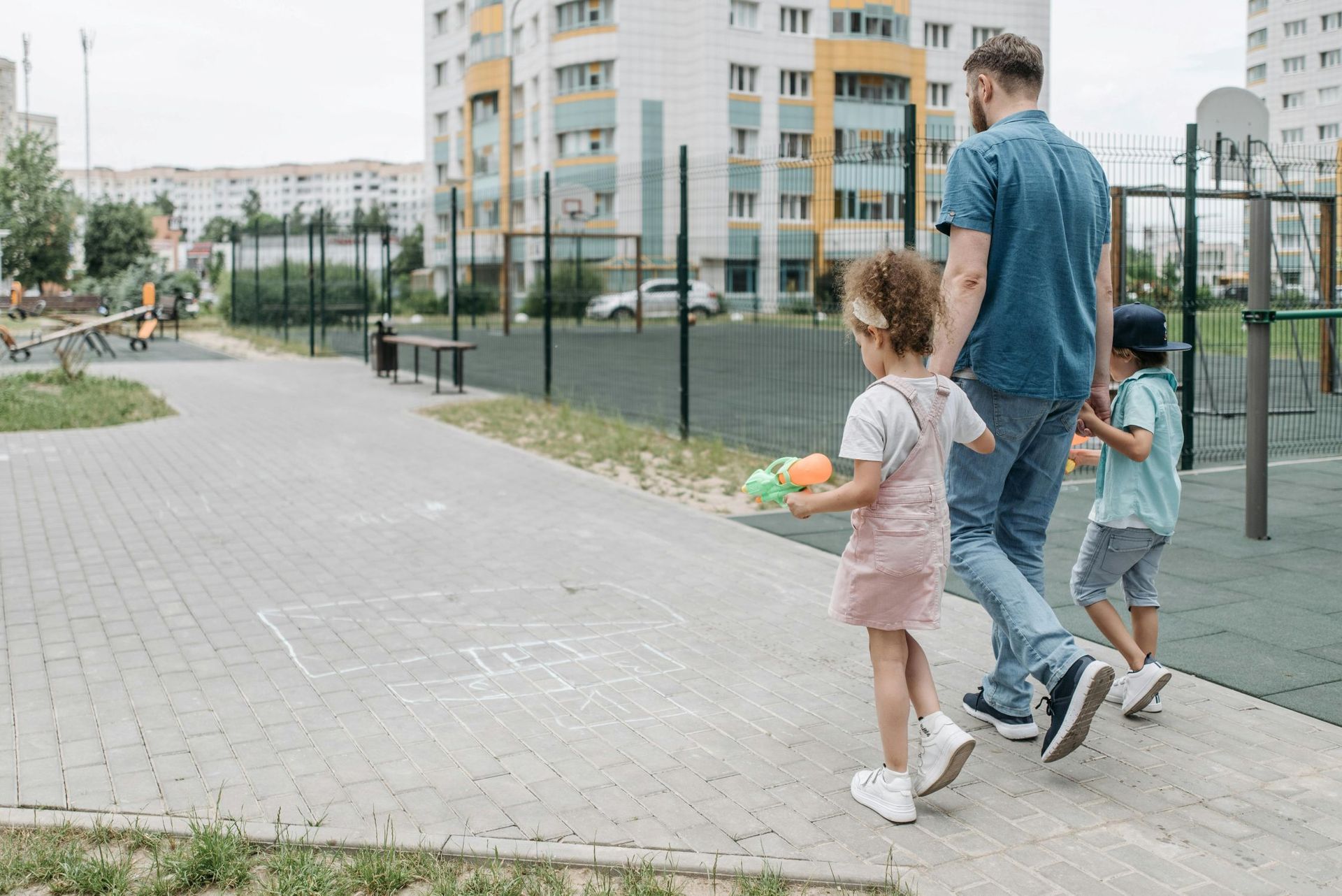 Father with 2 kids walking in a park.