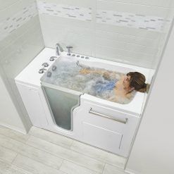 A woman is laying in a walk in tub with a door.