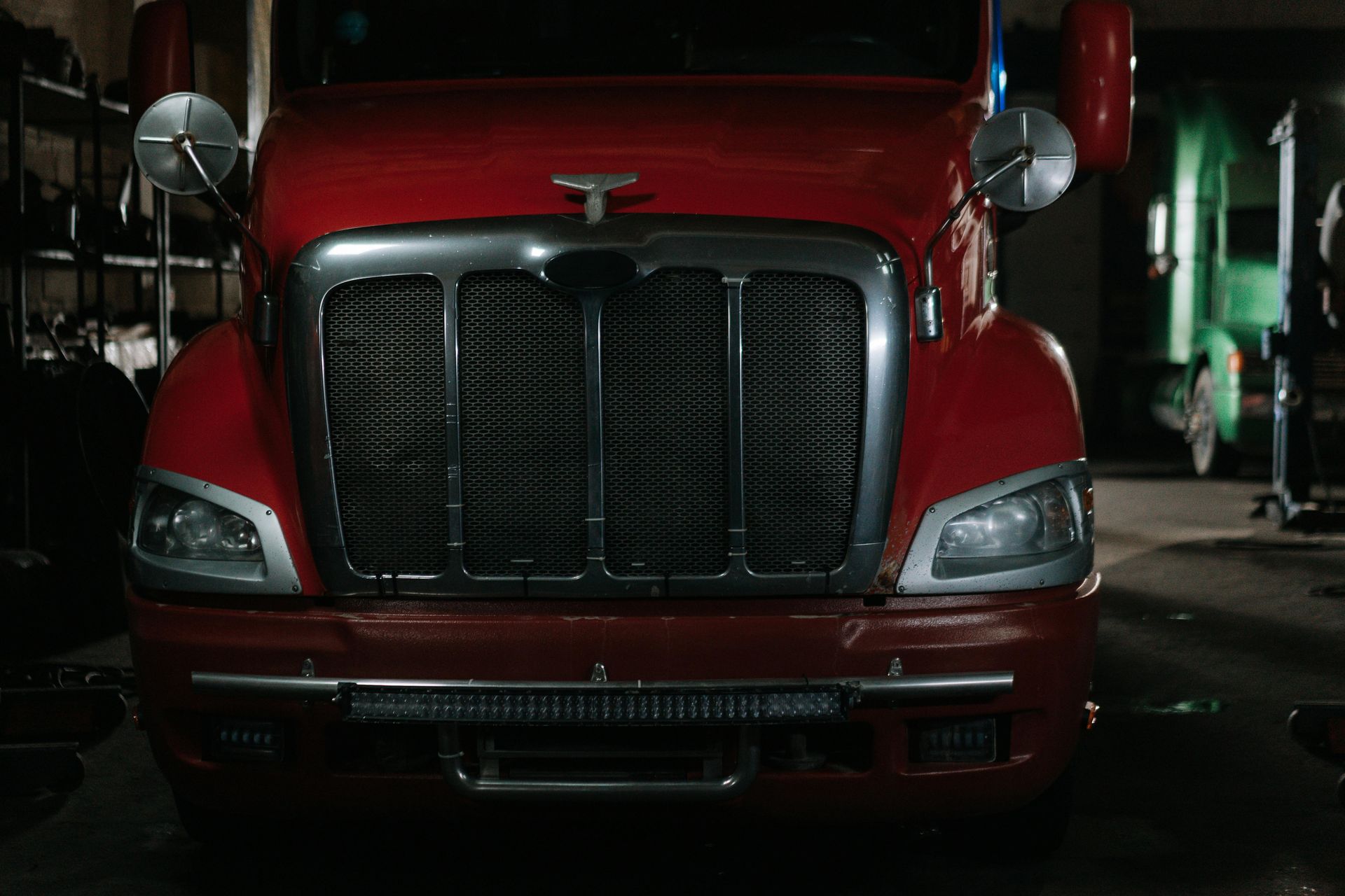 A red semi truck is parked in a garage.