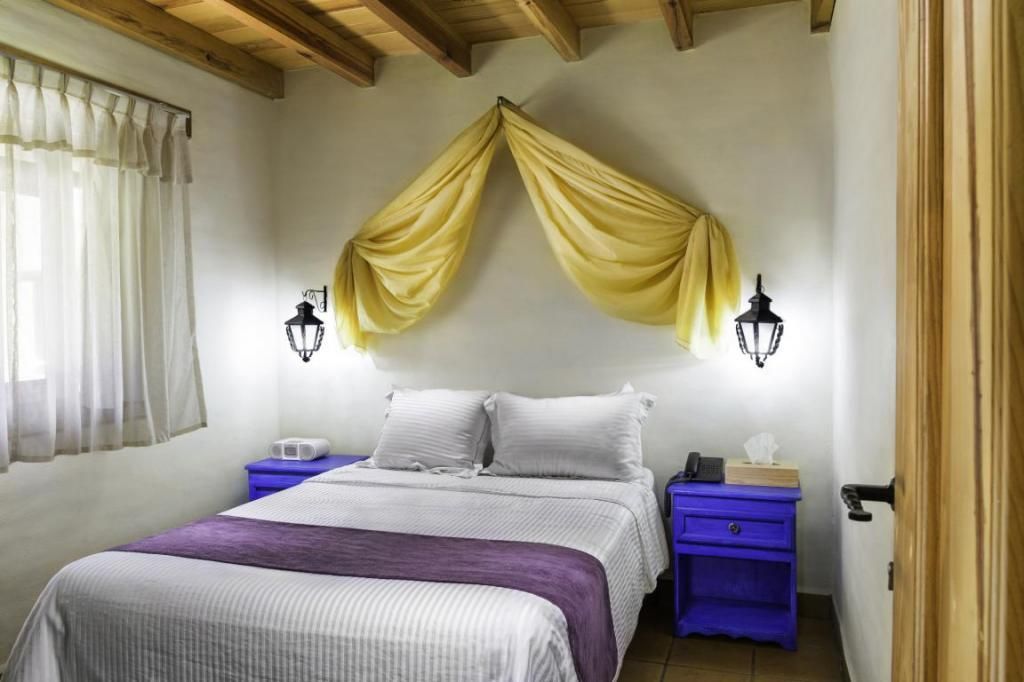 A bedroom with a bed , two nightstands , and a canopy over the bed.