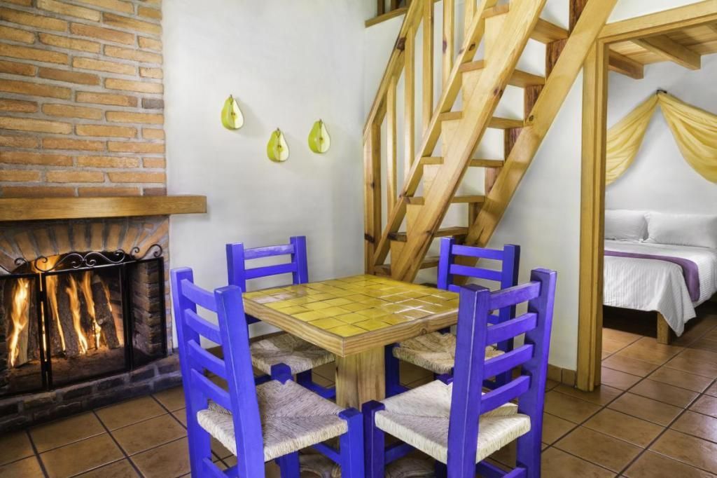 A dining room with a table and chairs and a fireplace.