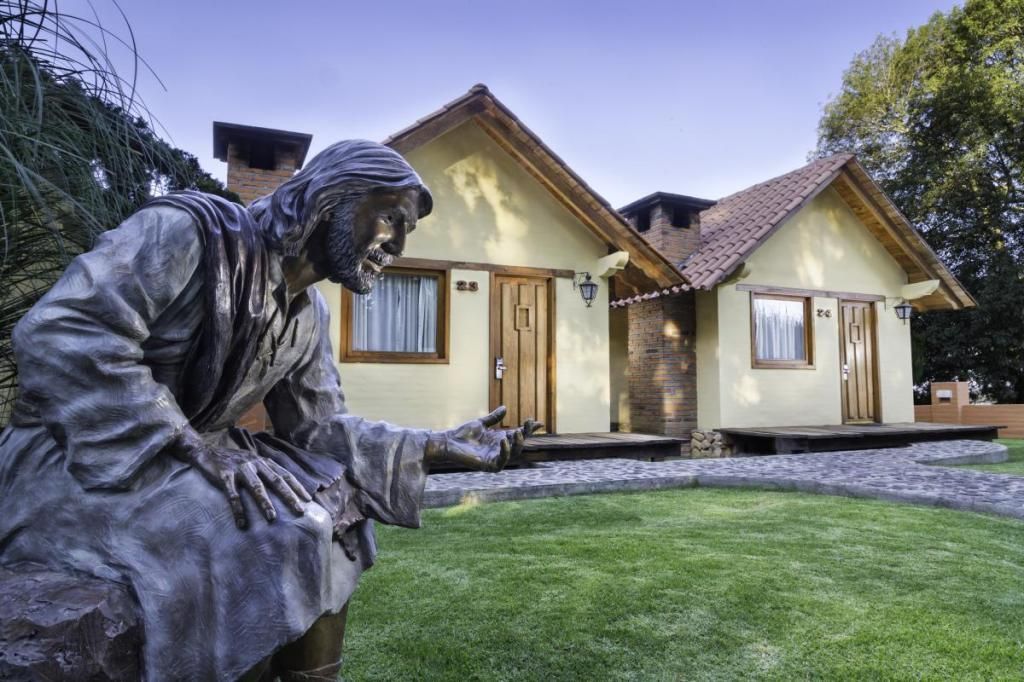 A statue of jesus is kneeling in front of a house.