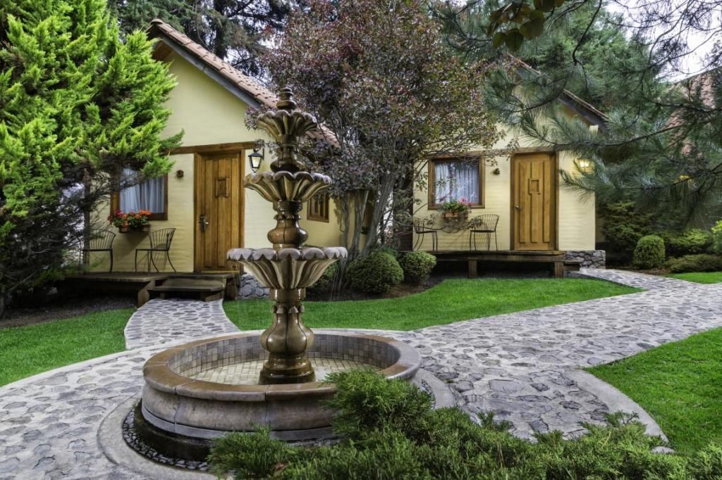 A small house with a fountain in front of it