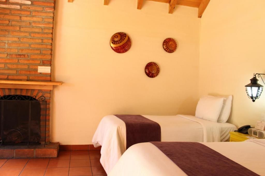 A hotel room with two beds and a fireplace.