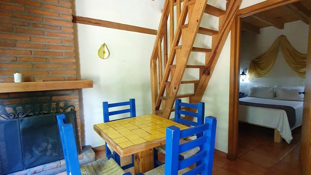 A room with a table and chairs in front of a fireplace.