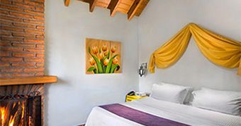 A bedroom with a bed , fireplace and painting on the wall.