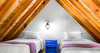 A bedroom with two beds and a blue nightstand in the attic.
