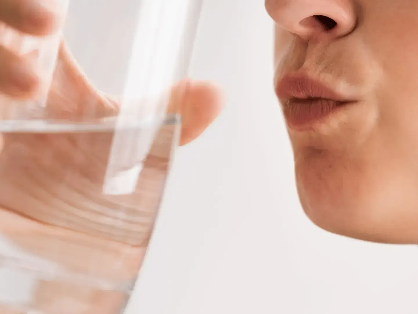 A woman is drinking a glass of water.