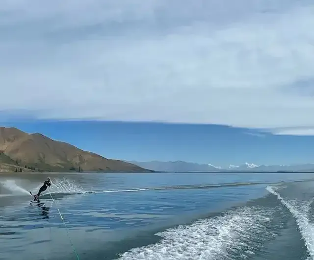 a person is water skiing in the ocean with mountains in the background