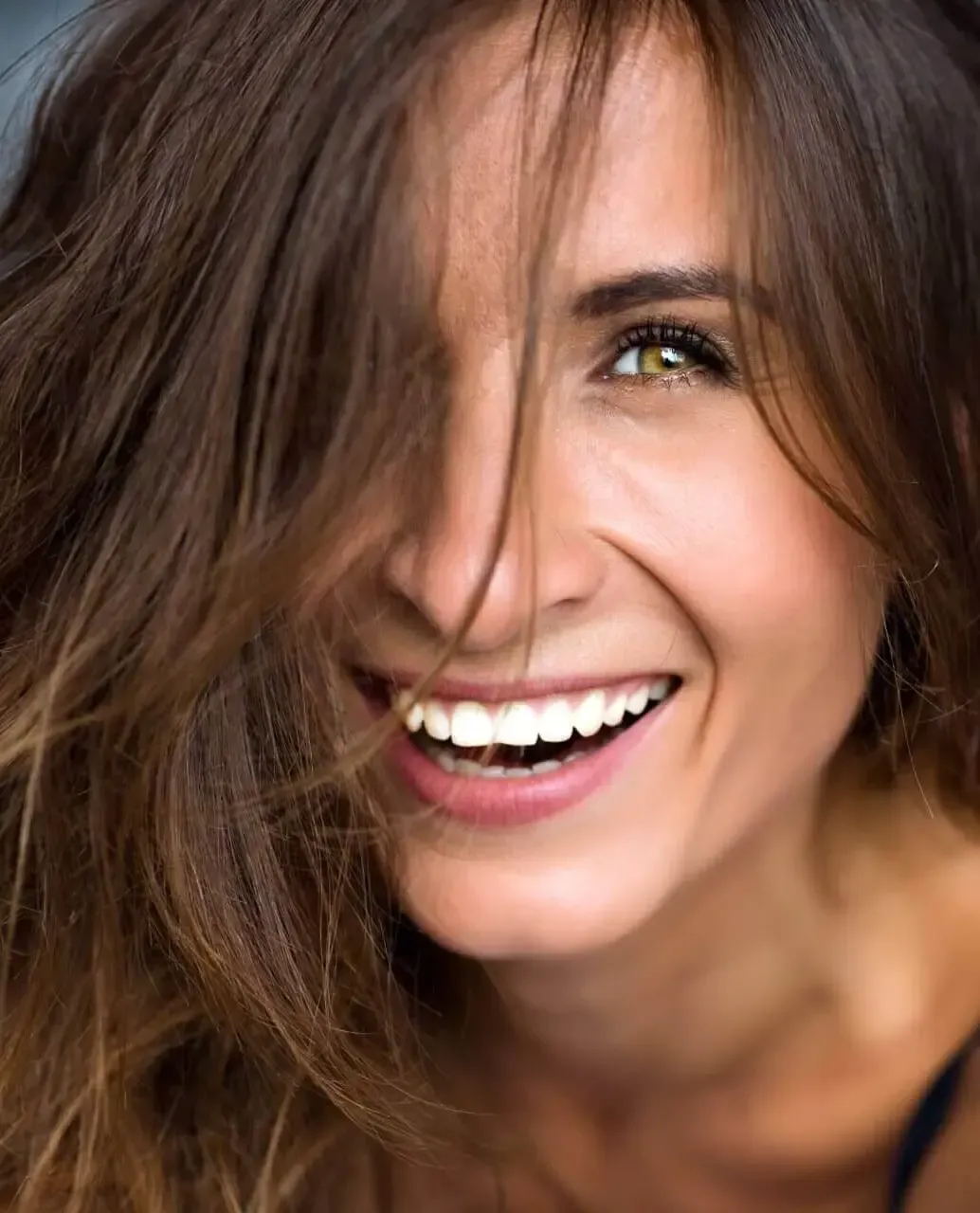 a close up of a woman 's face with her hair blowing in the wind .