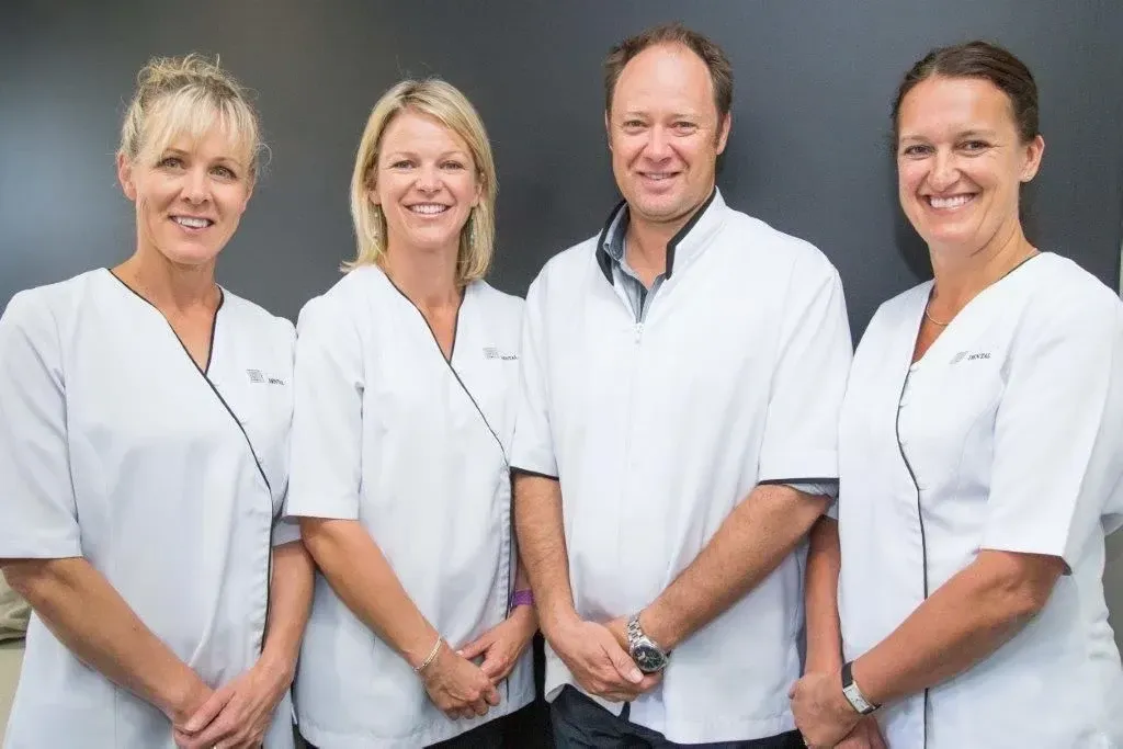 A group of people wearing white scrubs are posing for a picture.