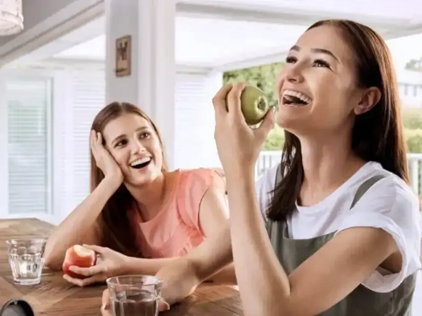 Women smiling eating an apple with Invisalign aligners