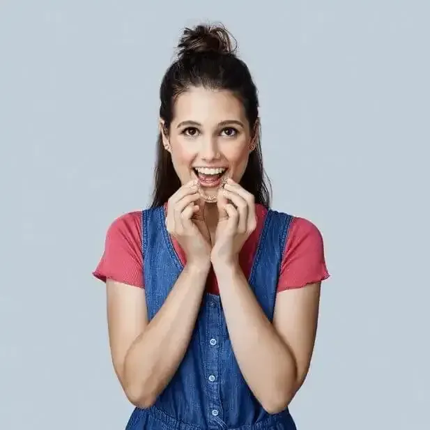 A woman in a denim dress is smiling and holding her mouth open.