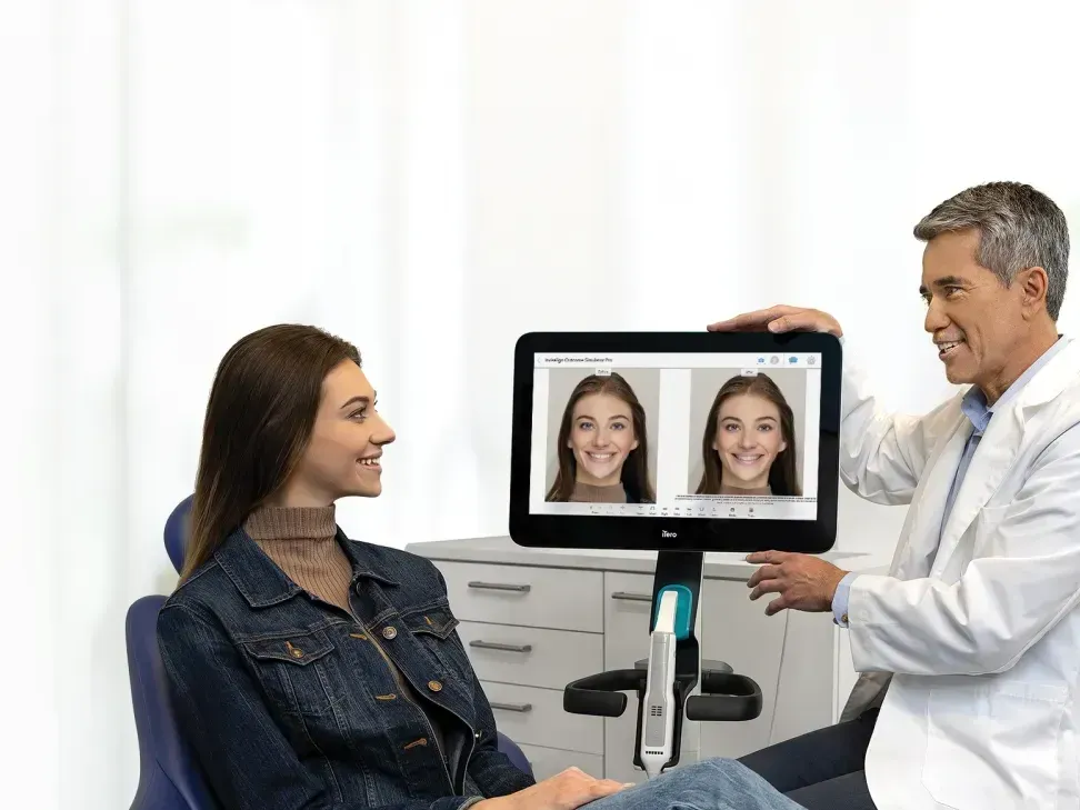 A dentist is showing a woman a picture of her face on a computer screen.