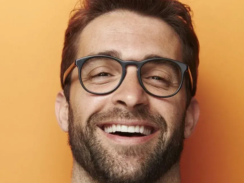 a man with glasses and a beard is smiling