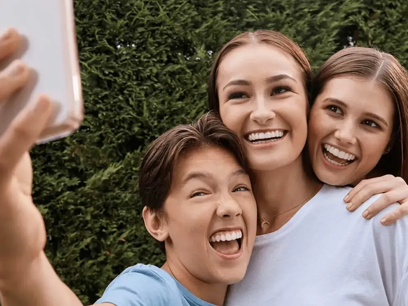 A group of young women are taking a selfie with a cell phone.