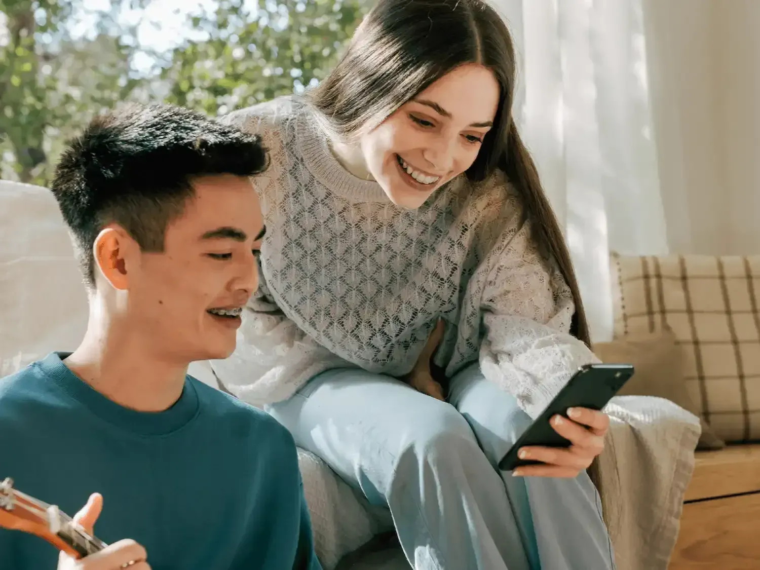 A man and a woman are sitting on a couch looking at a cell phone with their dental monitoring app