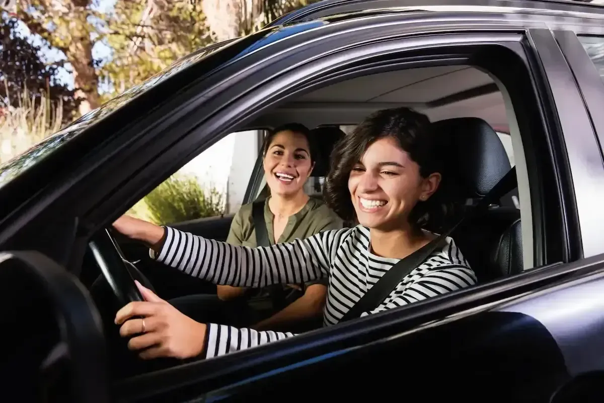 Two women are sitting in a car and smiling.