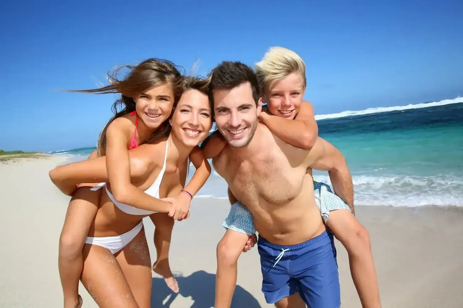 Parents Smiling At Beach With Kids