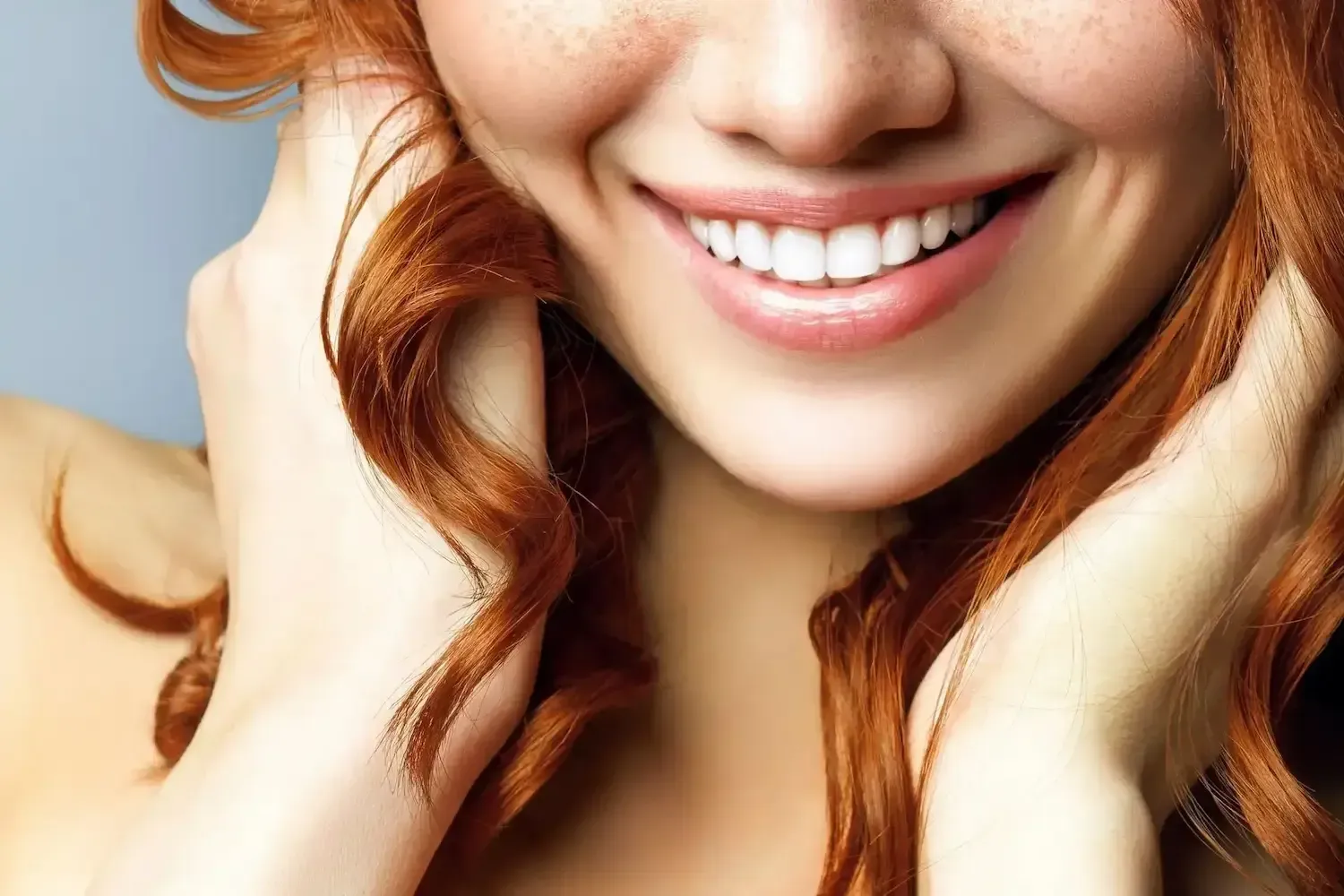 a close up of a woman 's face with red hair and freckles smiling .
