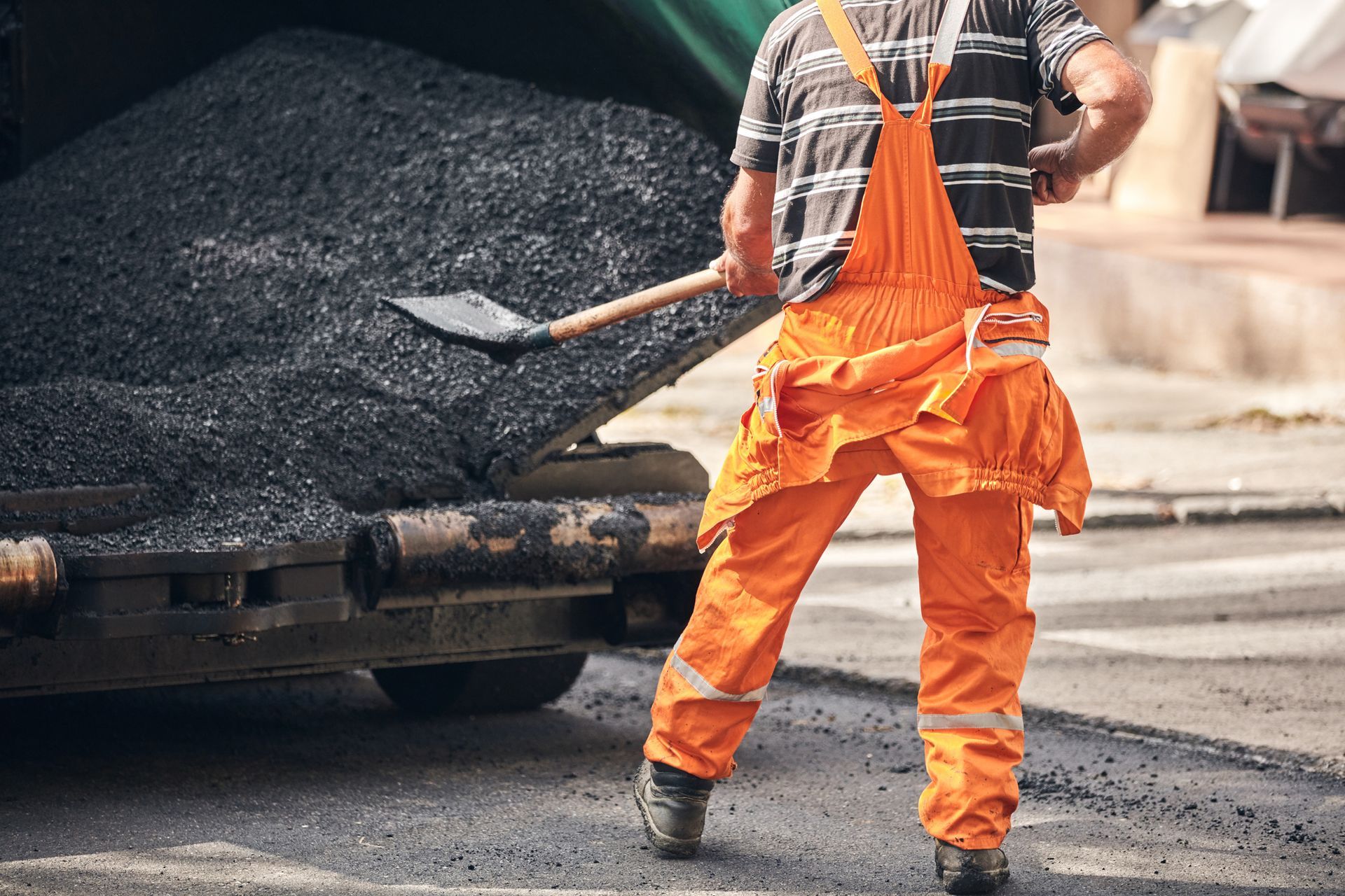 Construction workers working on a new asphalt layer on a public street.