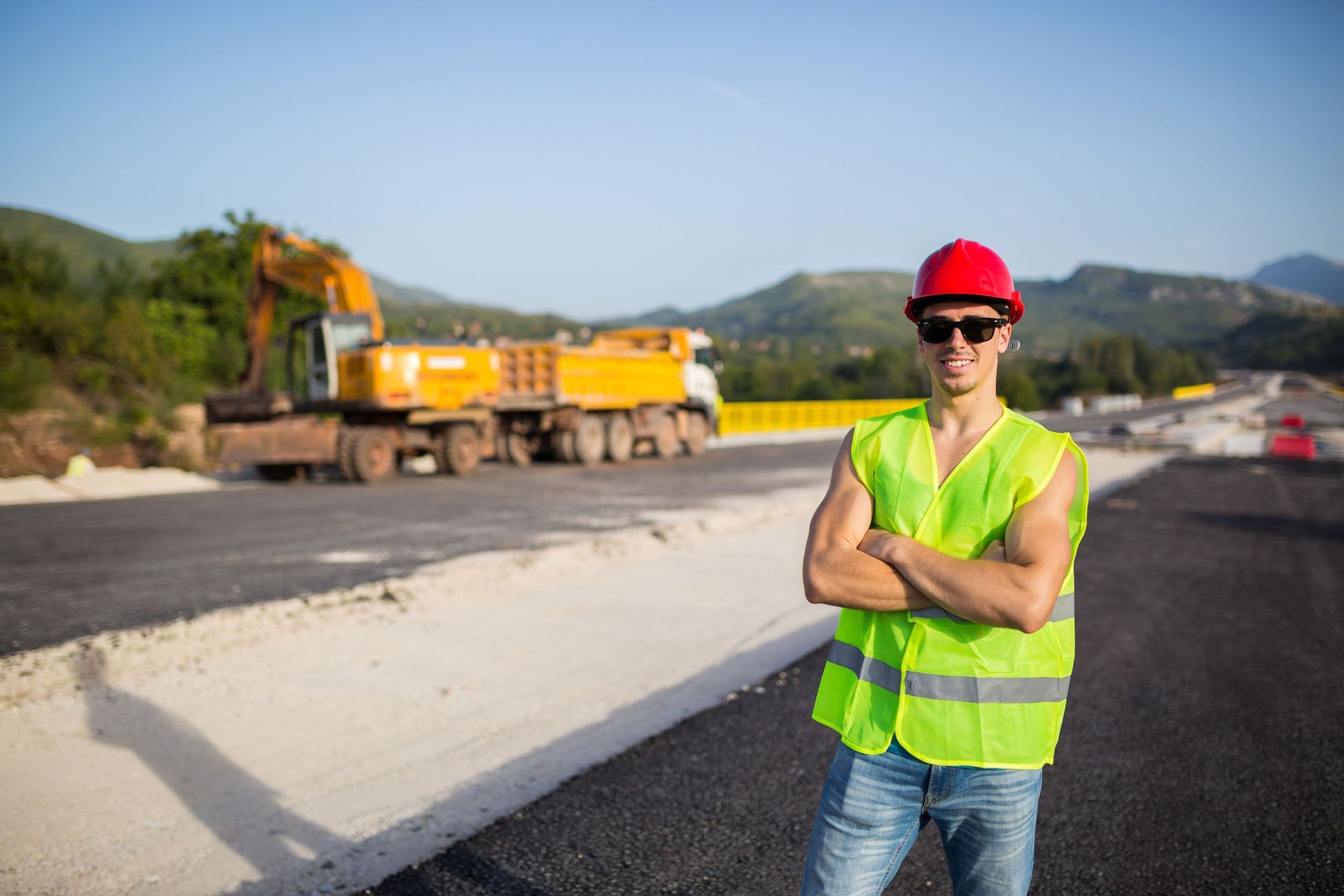 Construction worker in safety gear standing on a road under construction. Construction worker in safety gear standing on a road under construction.