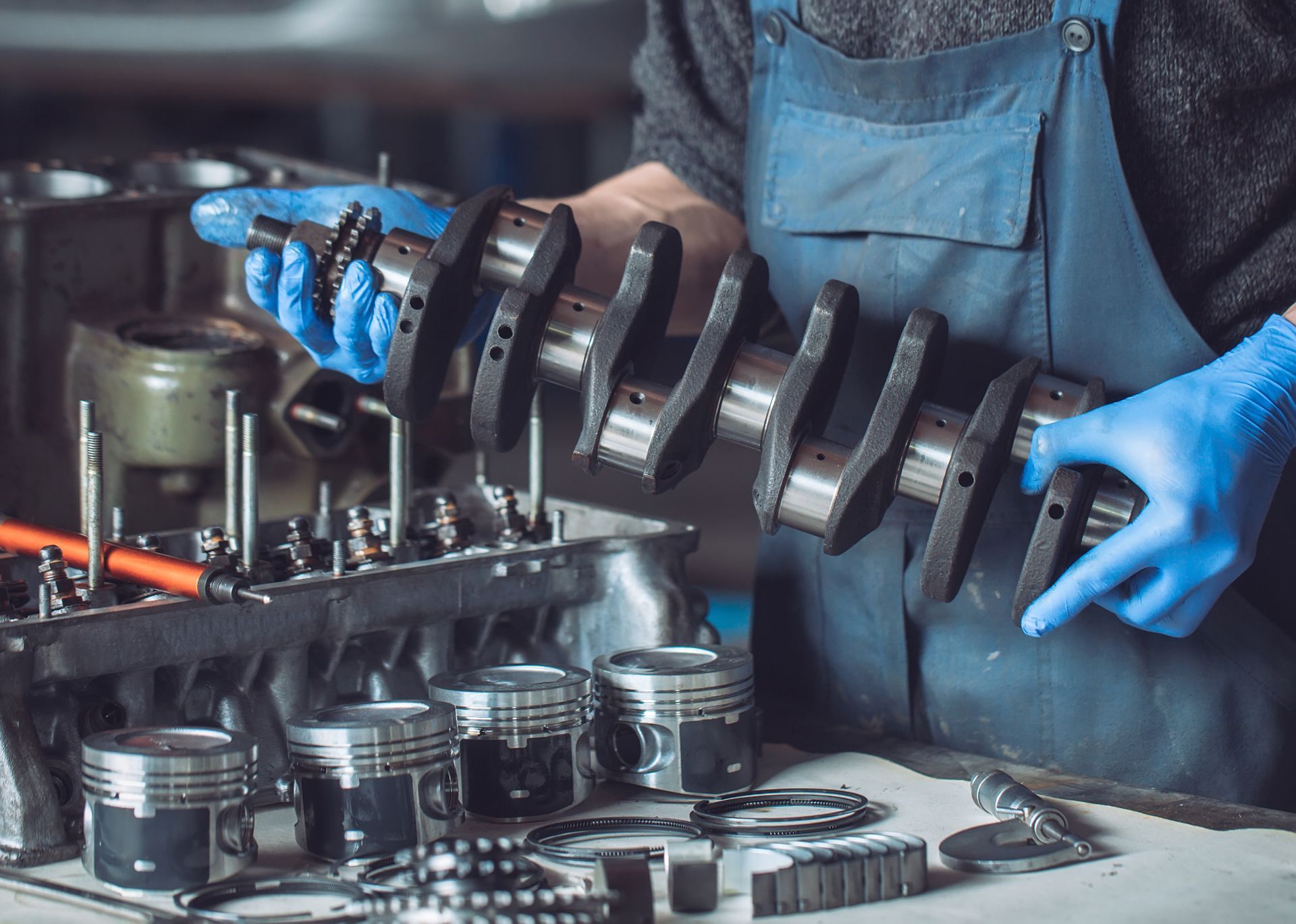 A man wearing blue gloves is working on a car engine.