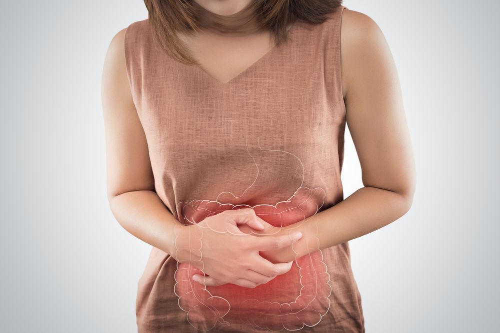 Woman in a brown shirt clutching stomach, with highlighted area indicating abdominal pain.