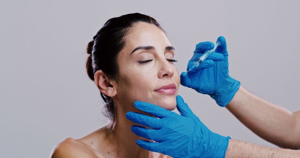 Woman receiving facial injections from gloved hands.