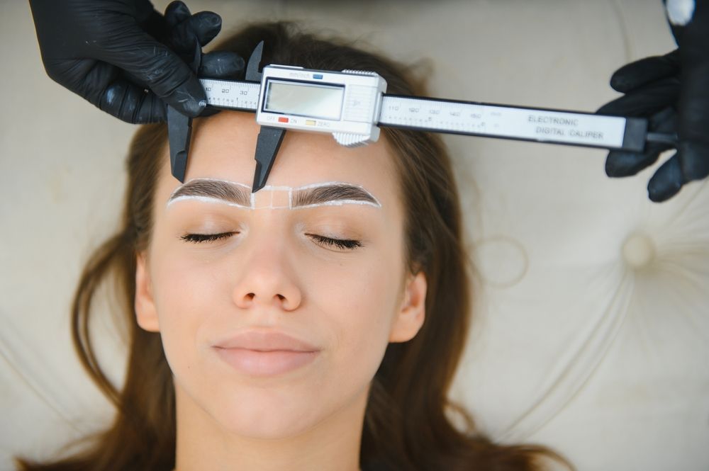 Person having eyebrows measured with digital calipers; white markings on brows.