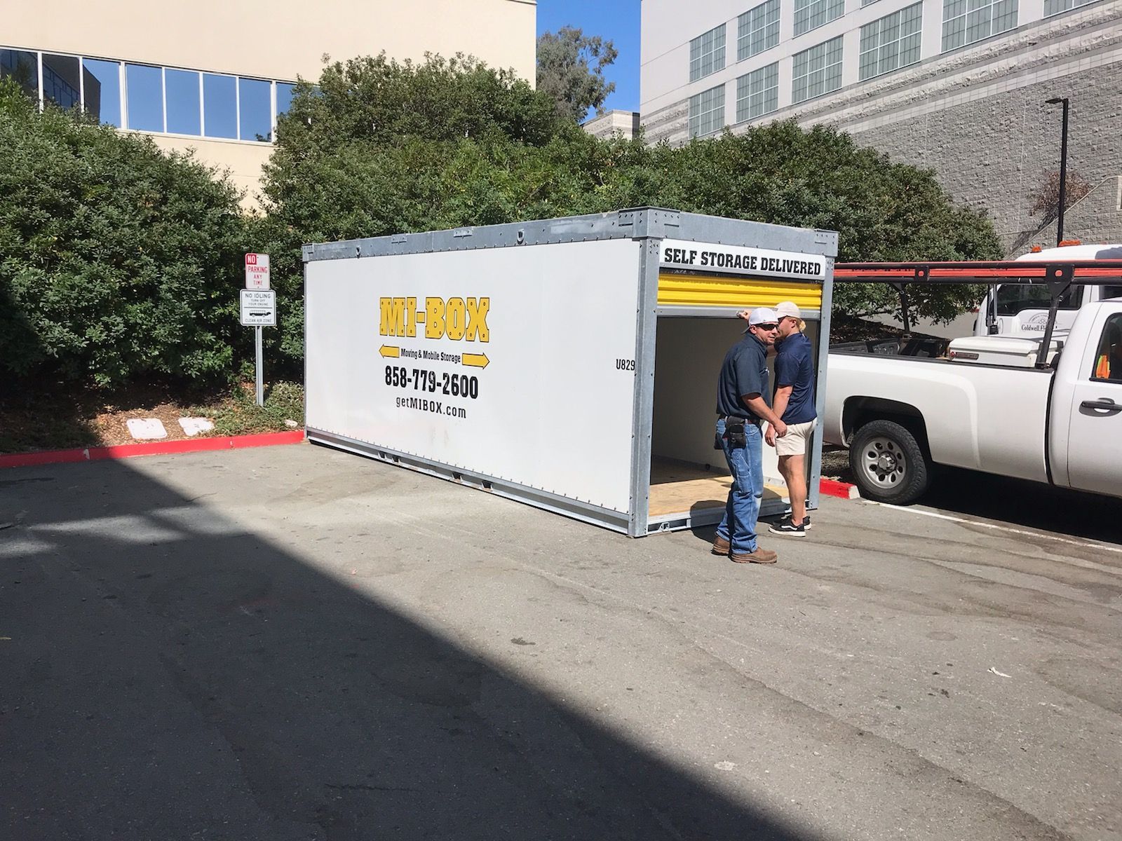 Two men are standing in front of a portable storage container that says key box