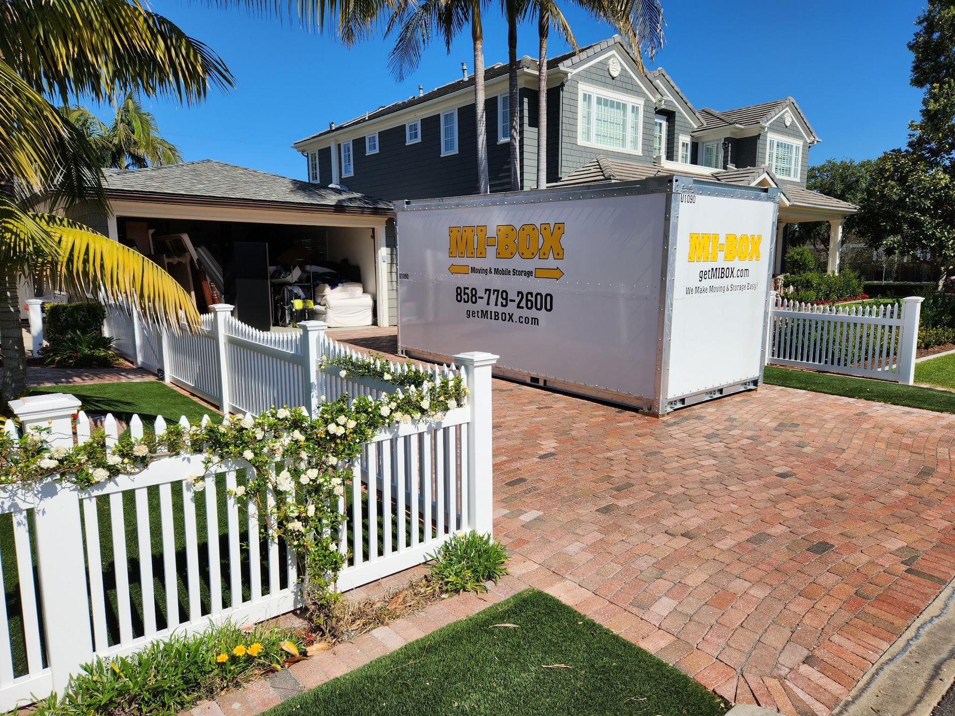 A white container is parked in front of a house.