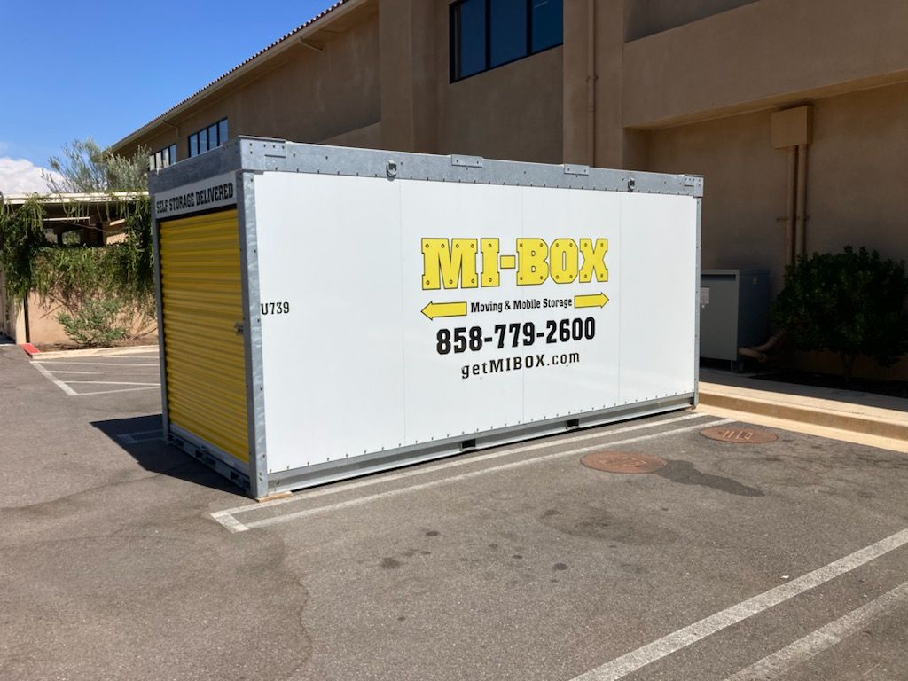 A white box with a yellow door is sitting in a parking lot.