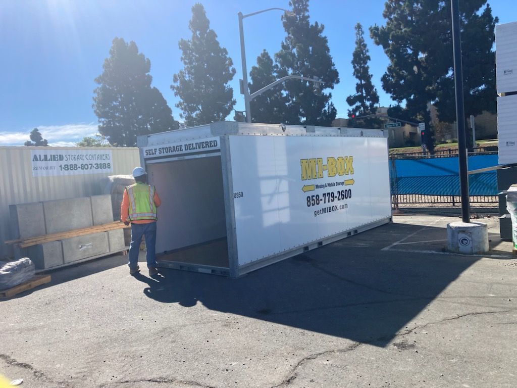 A man in a safety vest is standing next to a large white box.