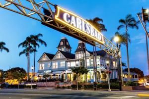 A large building with palm trees in front of it and a sign that says ' carlsbad ' on it.