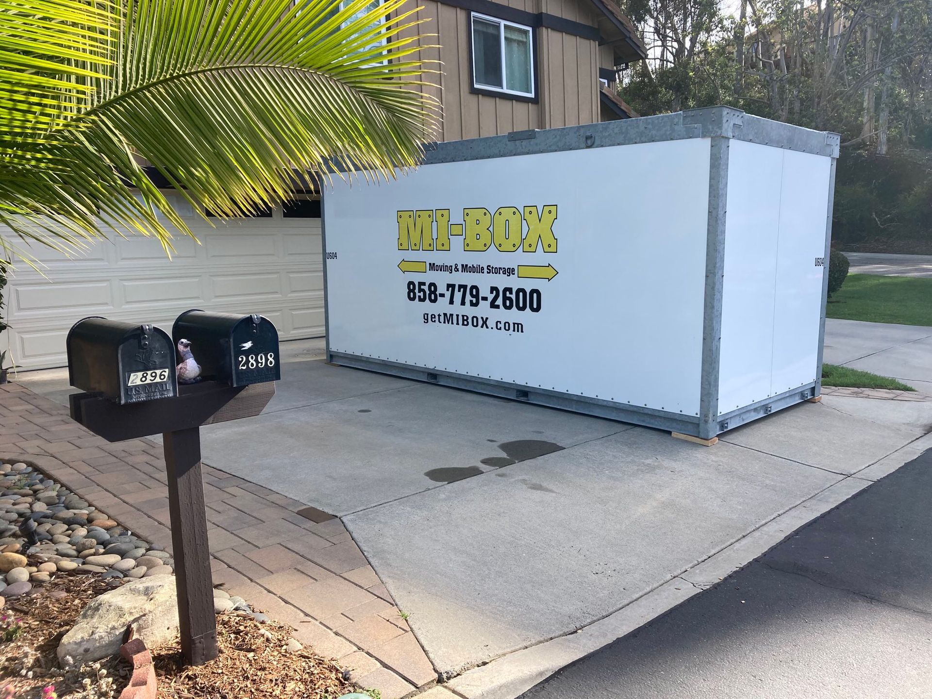 A white box is parked in front of a house next to a mailbox.