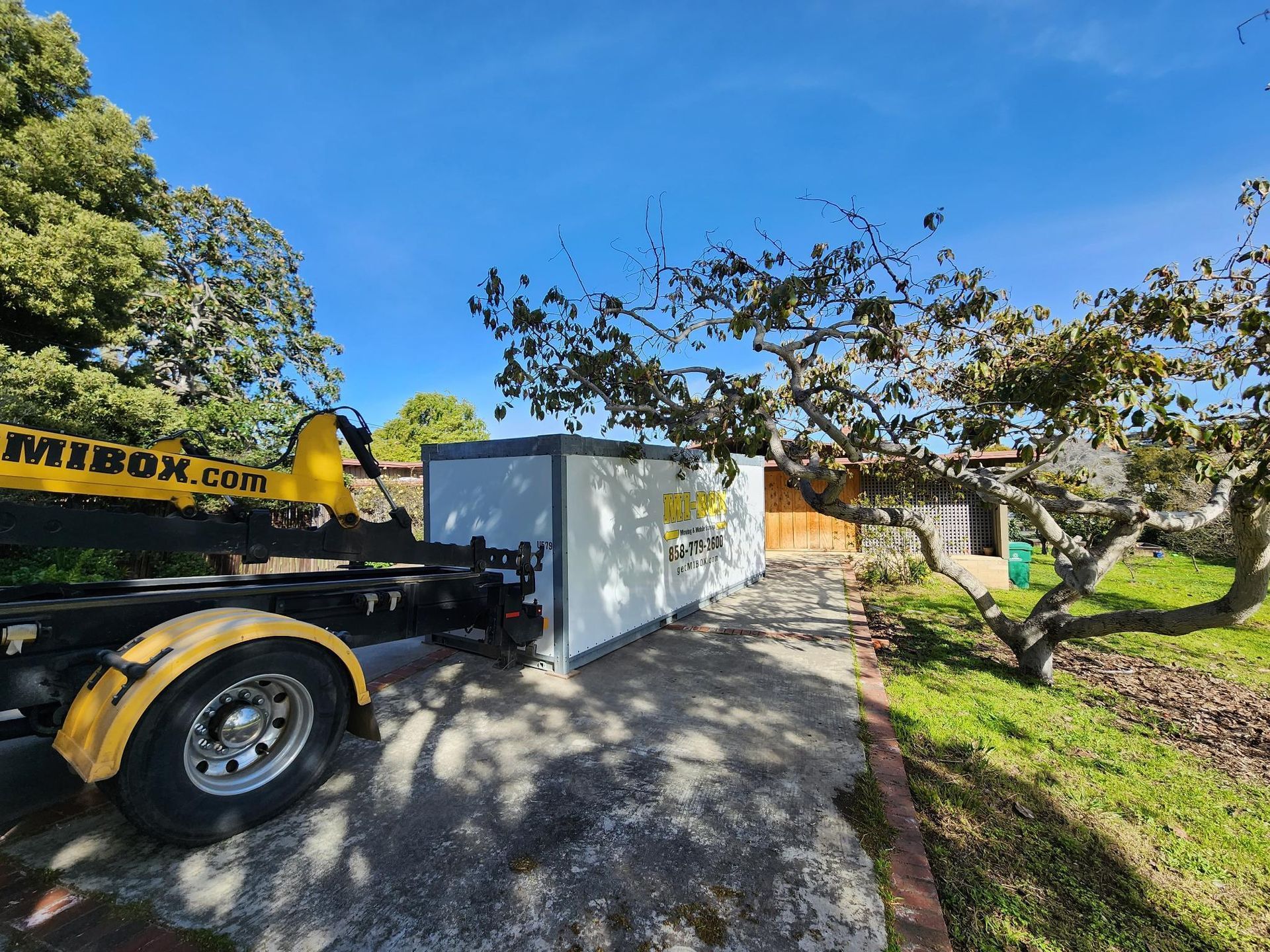 A yellow and black dump truck is parked in front of a house.