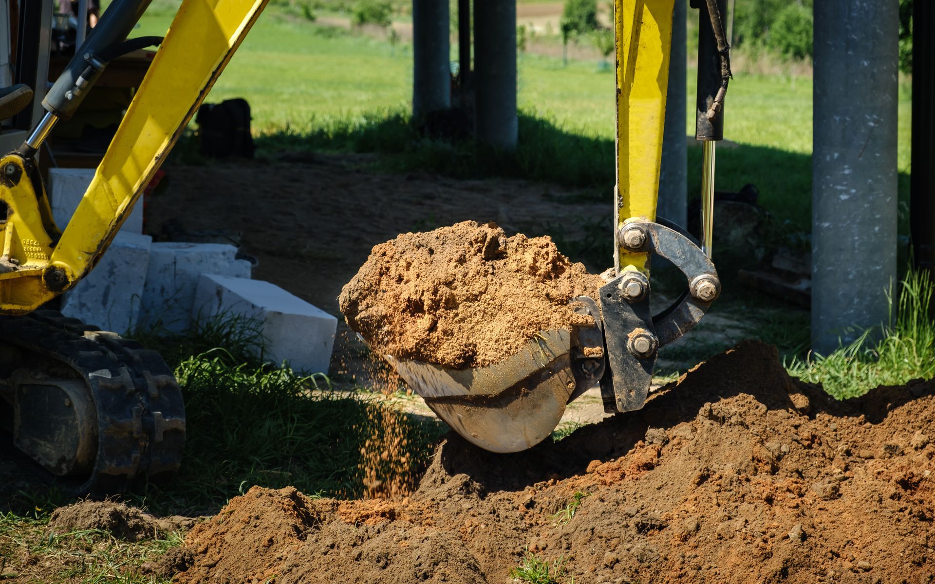 Une excavatrice jaune creuse un trou dans le sol.