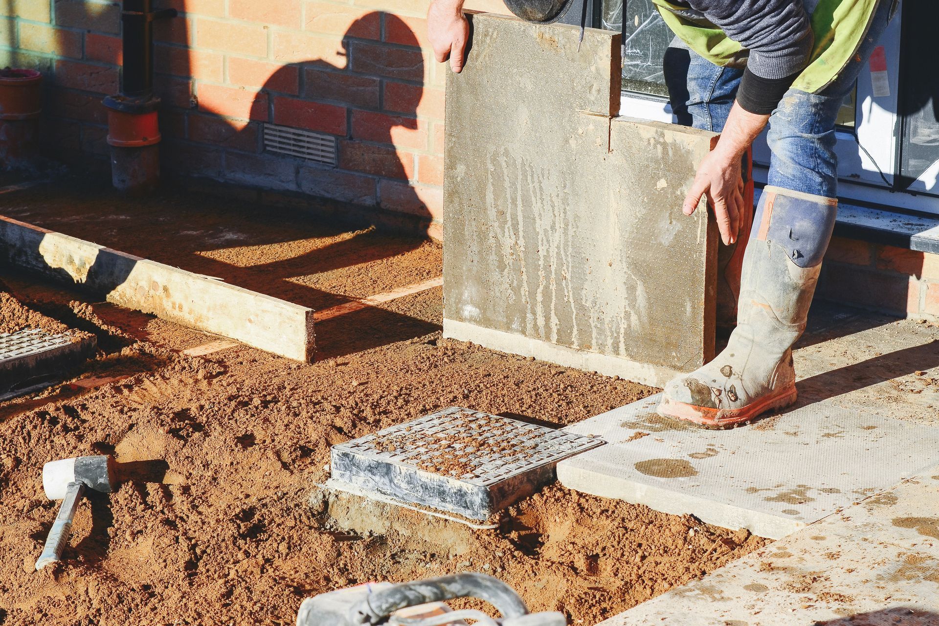 Un homme pose des dalles de béton sur un trottoir.