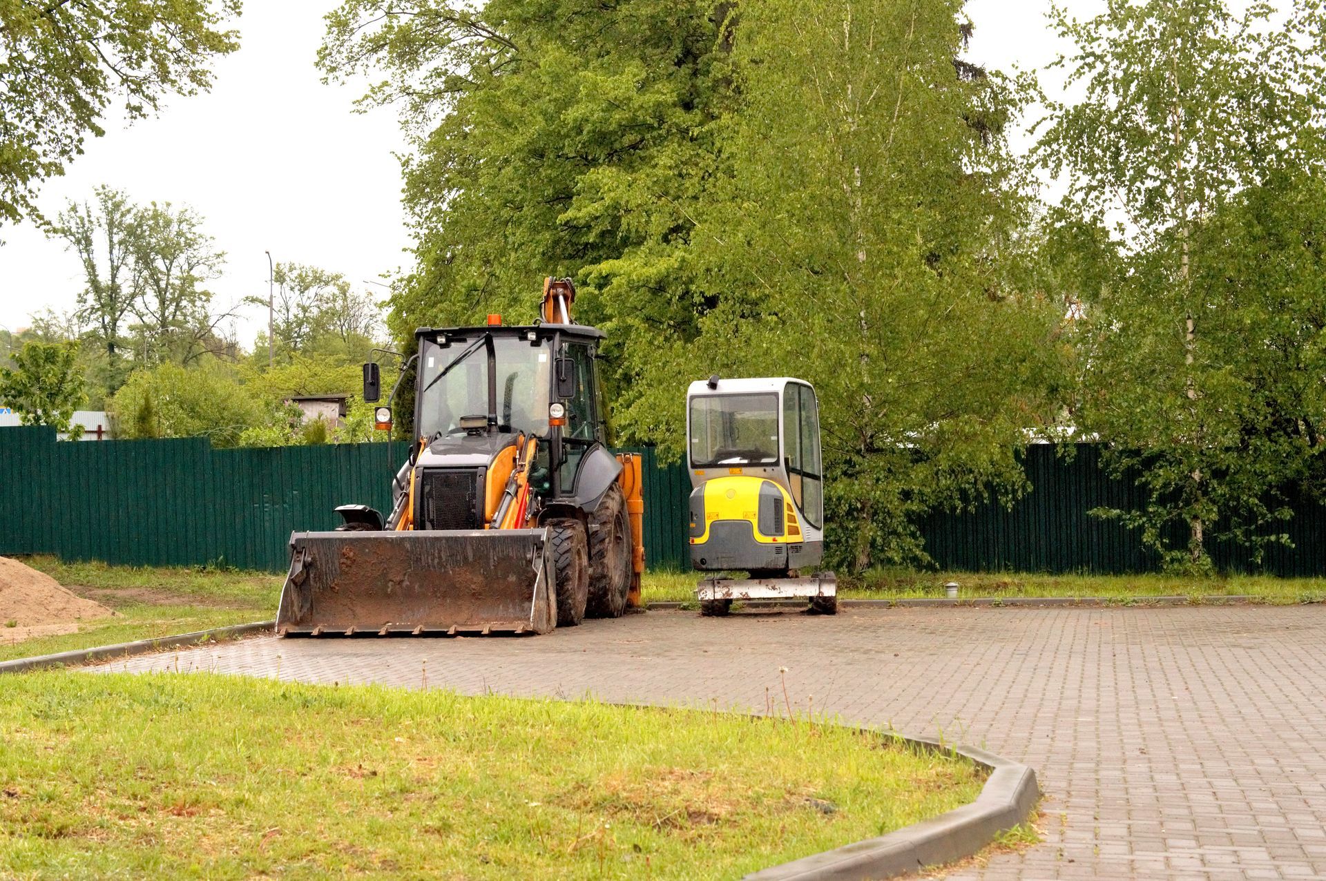Un bulldozer roule sur une route en briques à côté d'un bulldozer plus petit.