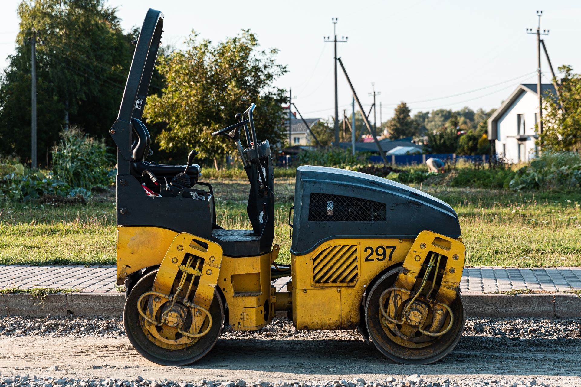 Un rouleau compresseur d'asphalte jaune et noir est garé sur le bord de la route.