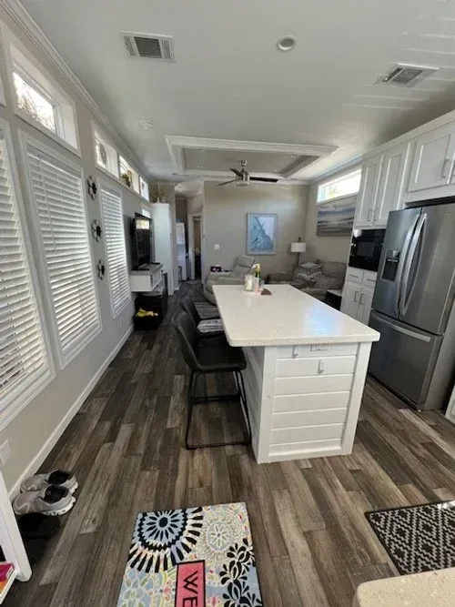 A light-filled kitchen with an island, stainless steel appliances, and a view into the living area.