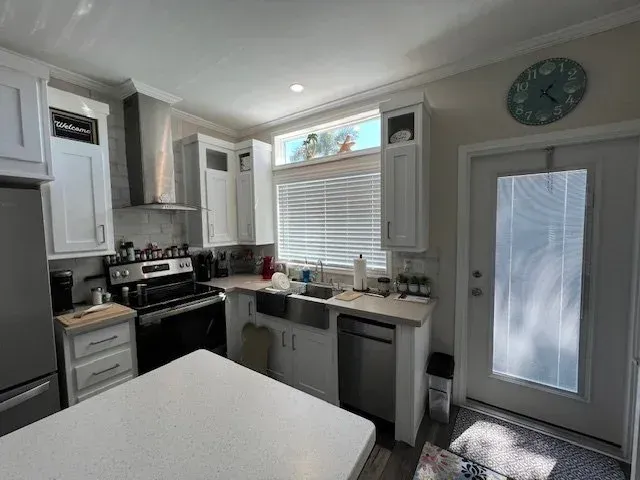 White kitchen with stainless steel appliances, white cabinets, and a quartz countertop island.