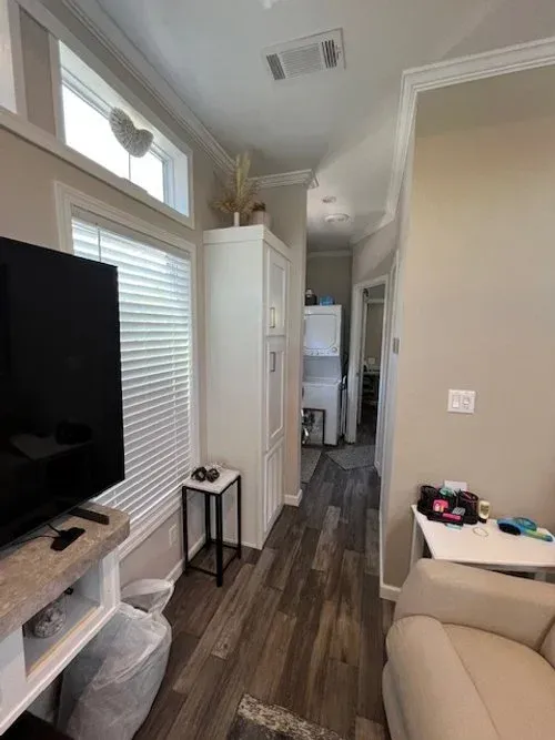 Narrow hallway in a house with a TV, laundry area, and small table.