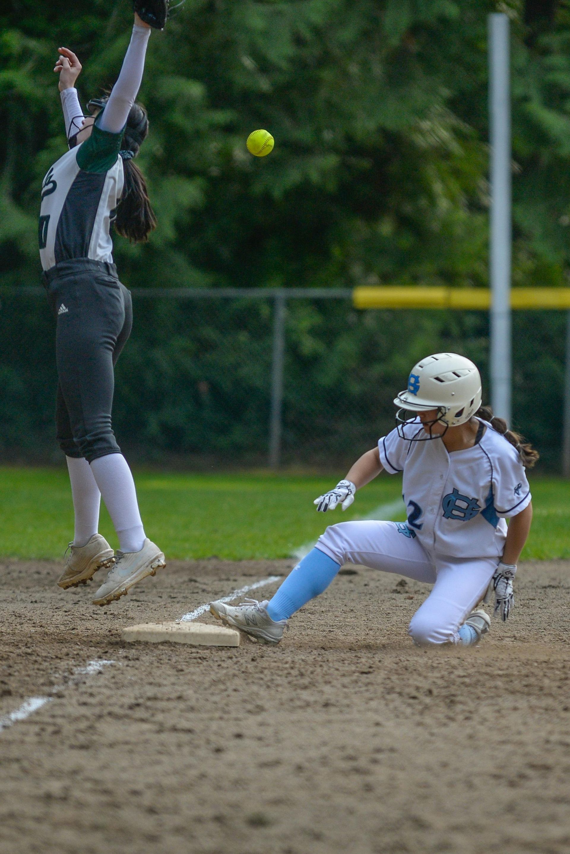 Baseball player sliding into home plate, catcher in front. Blue and gold uniforms, action shot.