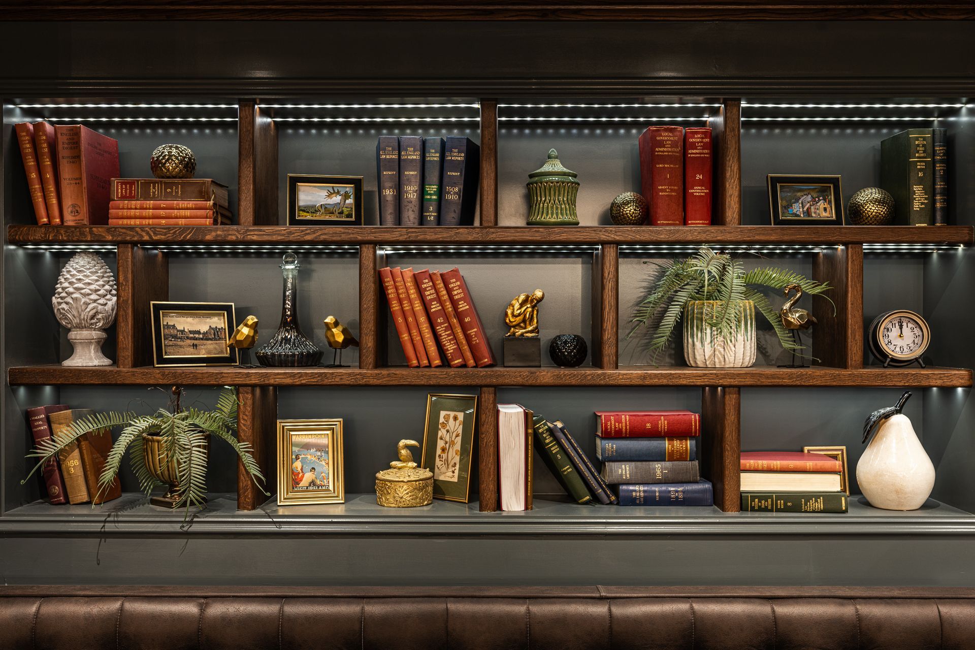 A bookshelf filled with books , pictures , vases , and clocks.