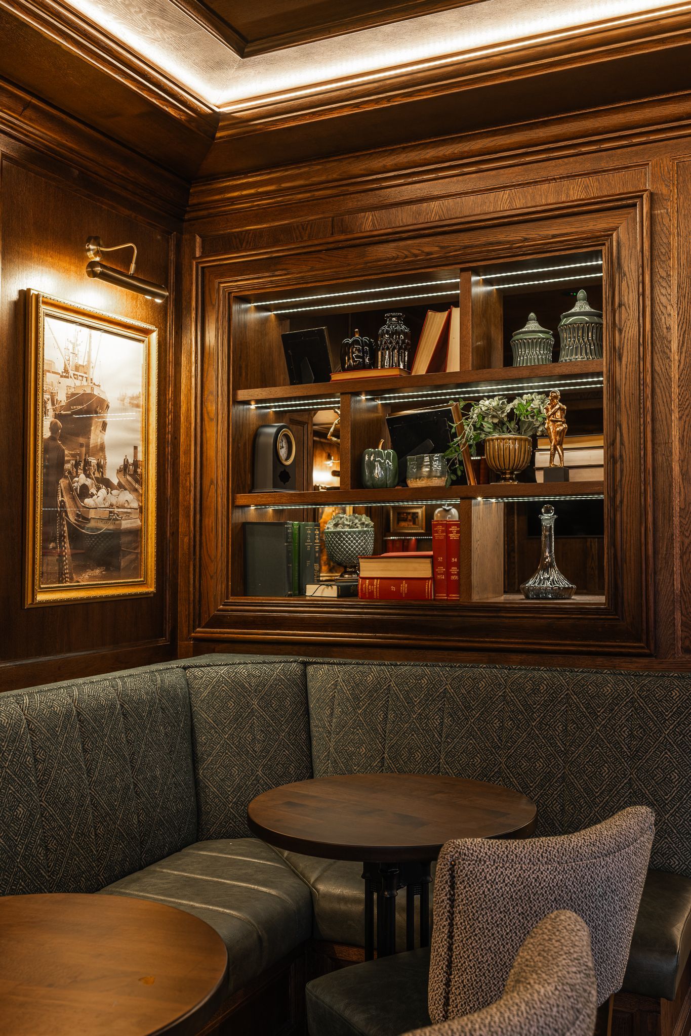 A corner of a room with tables and chairs and a bookshelf.