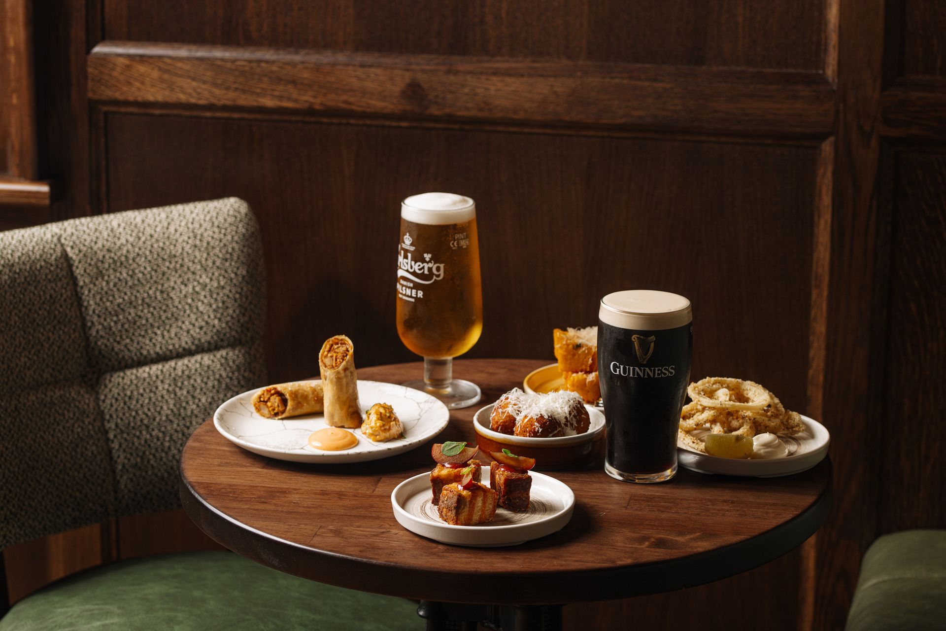 A table with plates of food and glasses of beer on it.