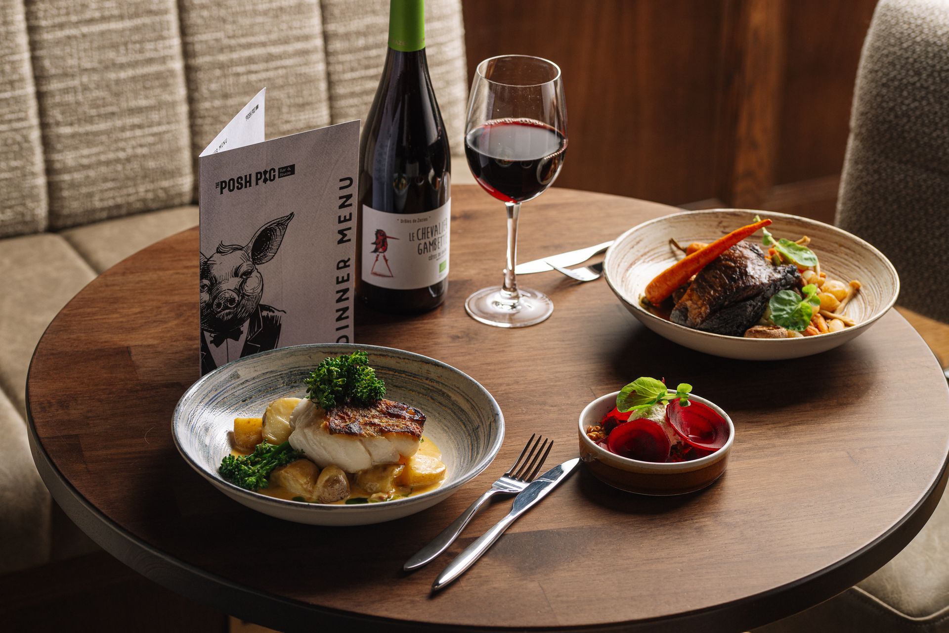 A wooden table topped with plates of food and a glass of wine.