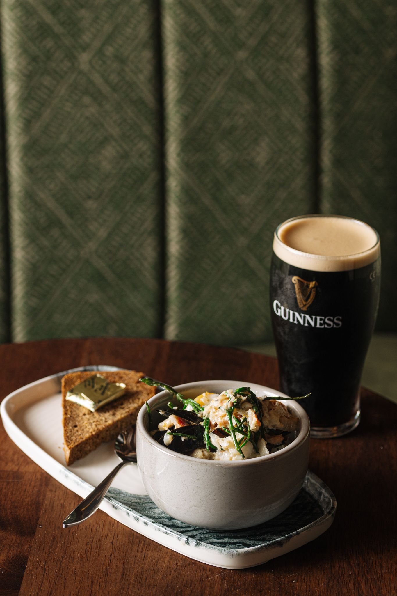 A bowl of food and a glass of beer are on a table.